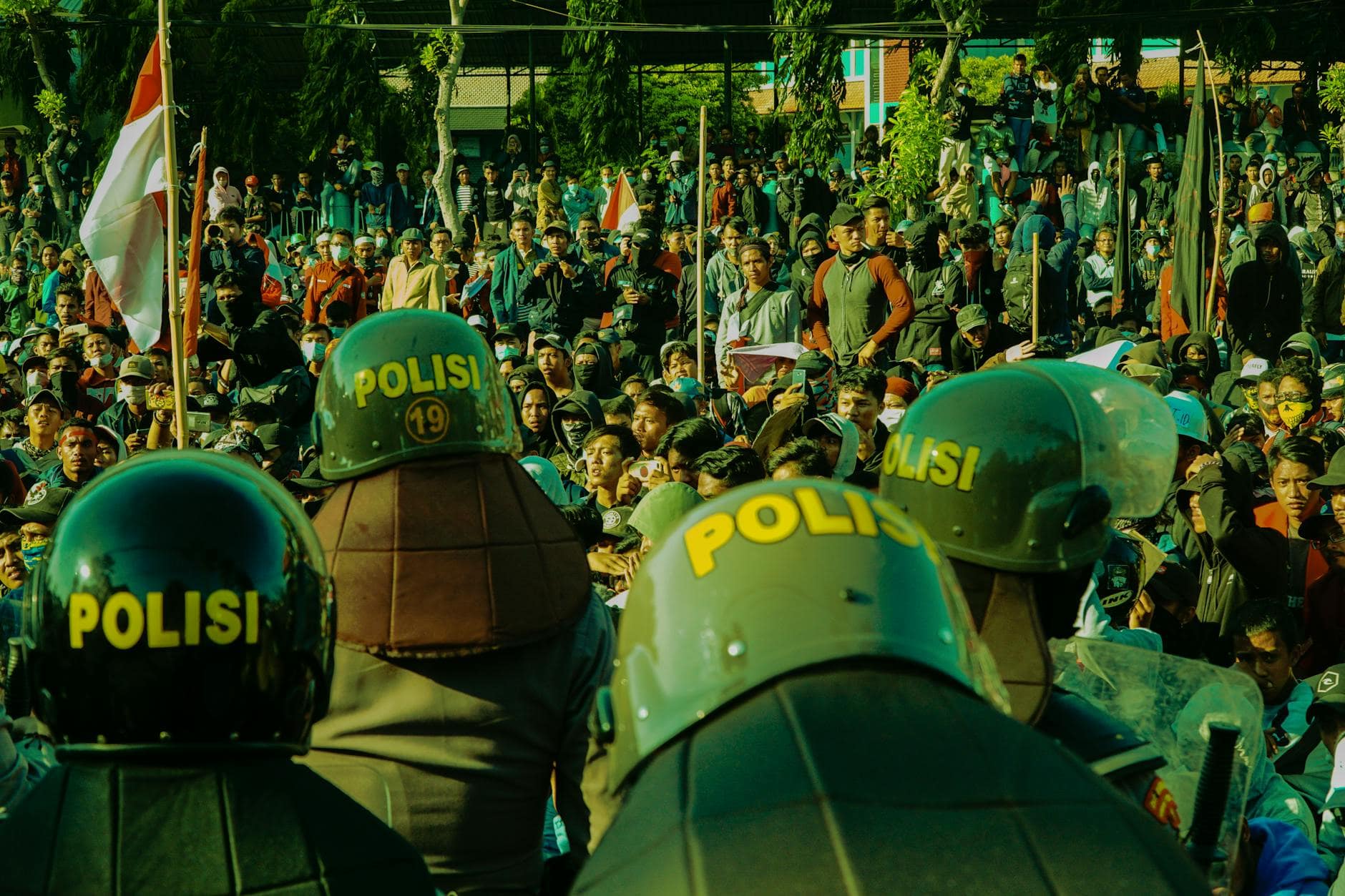 Demonstrasi massa menuntut transparansi dalam konflik politik nasional, menampilkan spanduk, polisi, dan suasana tegang